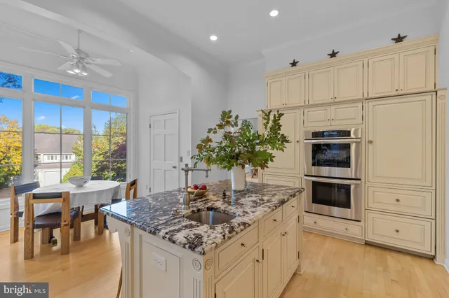 a kitchen with stainless steel appliances kitchen island granite countertop a stove a sink and a white cabinets