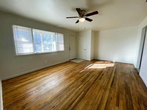 a view of a big room with wooden floor and windows