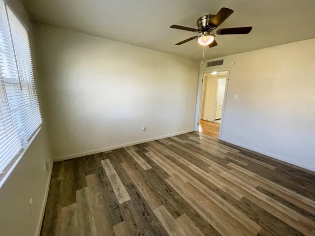 a view of empty room with wooden floor and fan
