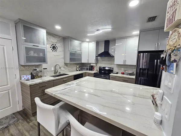 a kitchen with stainless steel appliances a sink a stove a refrigerator cabinets and a dining table