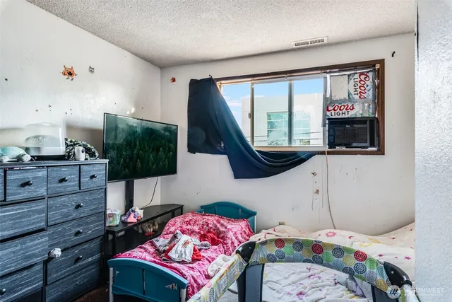 a bedroom with a bed a flat screen tv and a window