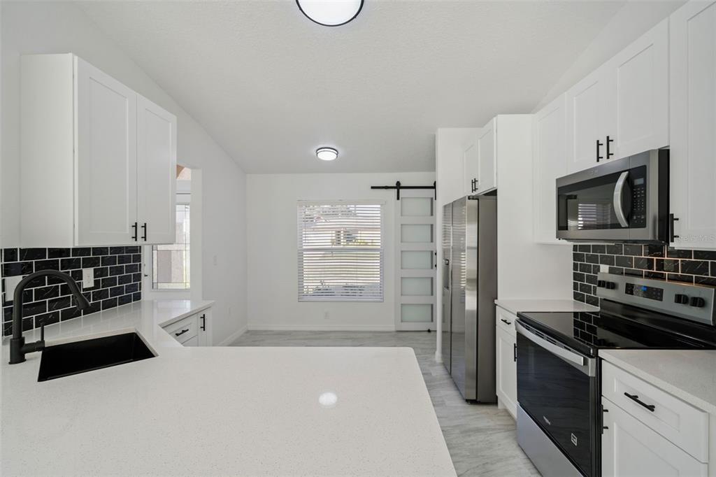 3215 Colusa Street Deltona, FL 32738 - Photo 19 of 32 a kitchen with granite countertop a refrigerator and a stove top oven