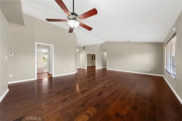 a view of an empty room with window and wooden floor