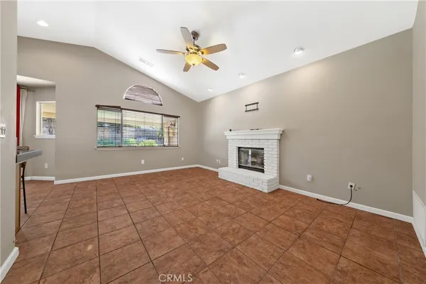 a view of an empty room with window and chandelier fan
