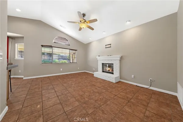 a view of an empty room with window and chandelier fan