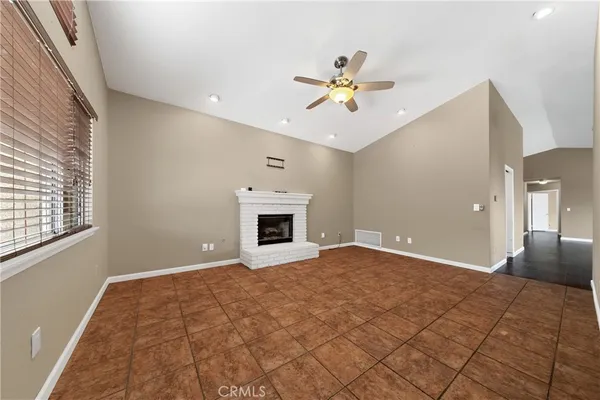 a view of an empty room with chandelier fan and a window