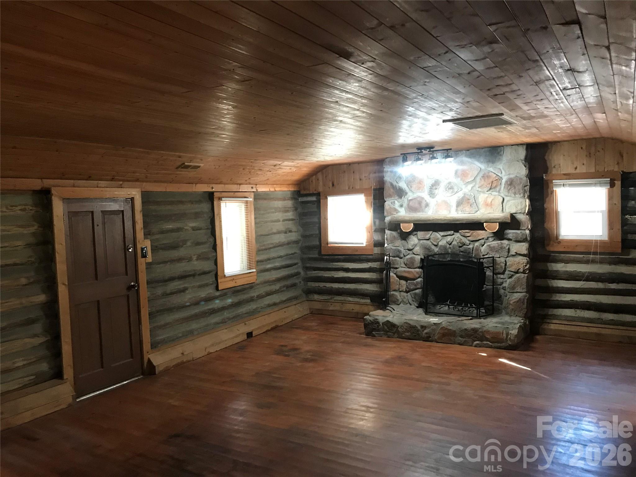 545 Avery Creek Road Arden, NC 28704 - Photo 32 of 35 an empty room with wooden floor fireplace and windows