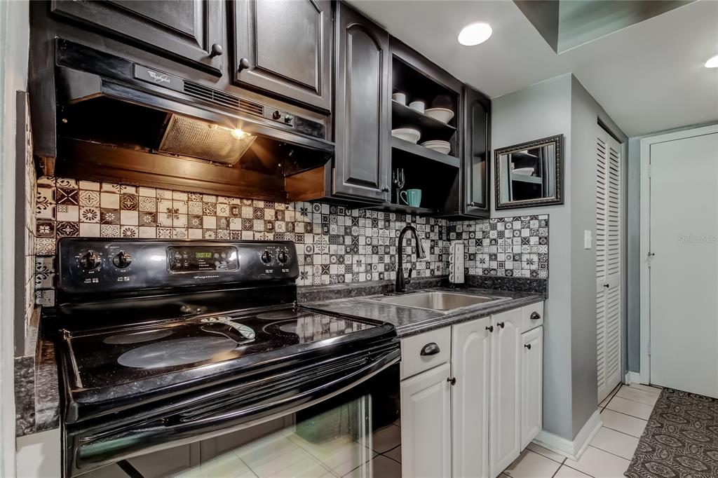4775 Cove Circle, Unit 1105 St. Petersburg, FL 33708 - Photo 6 of 40 a kitchen with stainless steel appliances granite countertop a stove and a microwave