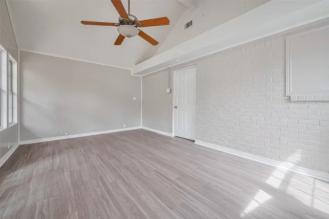 an empty room with wooden floor ceiling fan and window