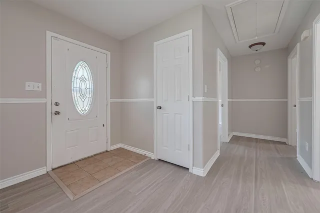 an empty room with wooden floor mirror and entrance