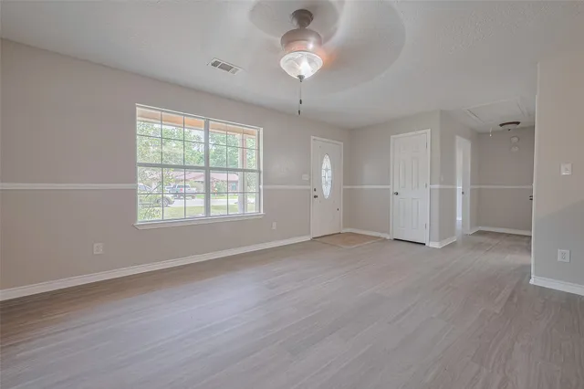 an empty room with wooden floor and windows