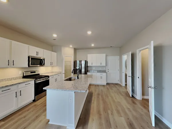 a large kitchen with stainless steel appliances granite countertop a lot of counter space and wooden floor
