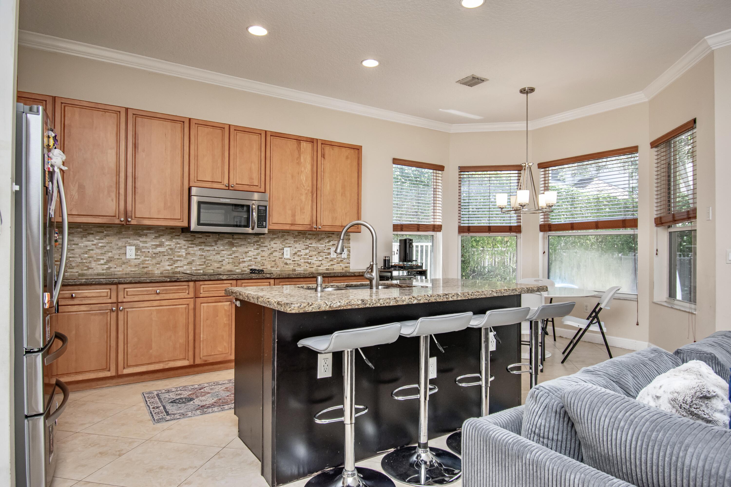 9851 Palma Vista Way Boca Raton, FL 33428 - Photo 15 of 33 a kitchen with stainless steel appliances granite countertop a stove a sink a microwave a dining table and chairs