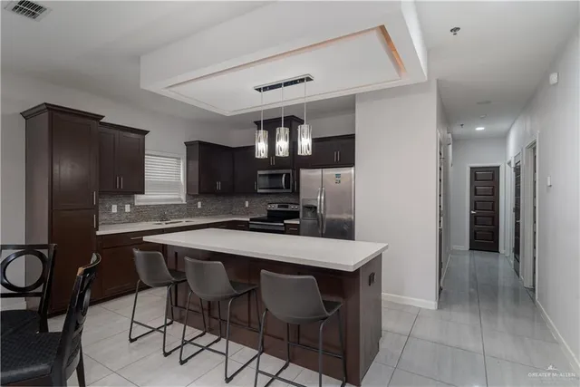 a kitchen with stainless steel appliances a dining table chairs refrigerator and sink