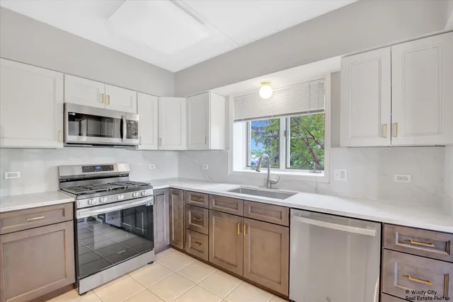 a kitchen with cabinets appliances a sink and a window