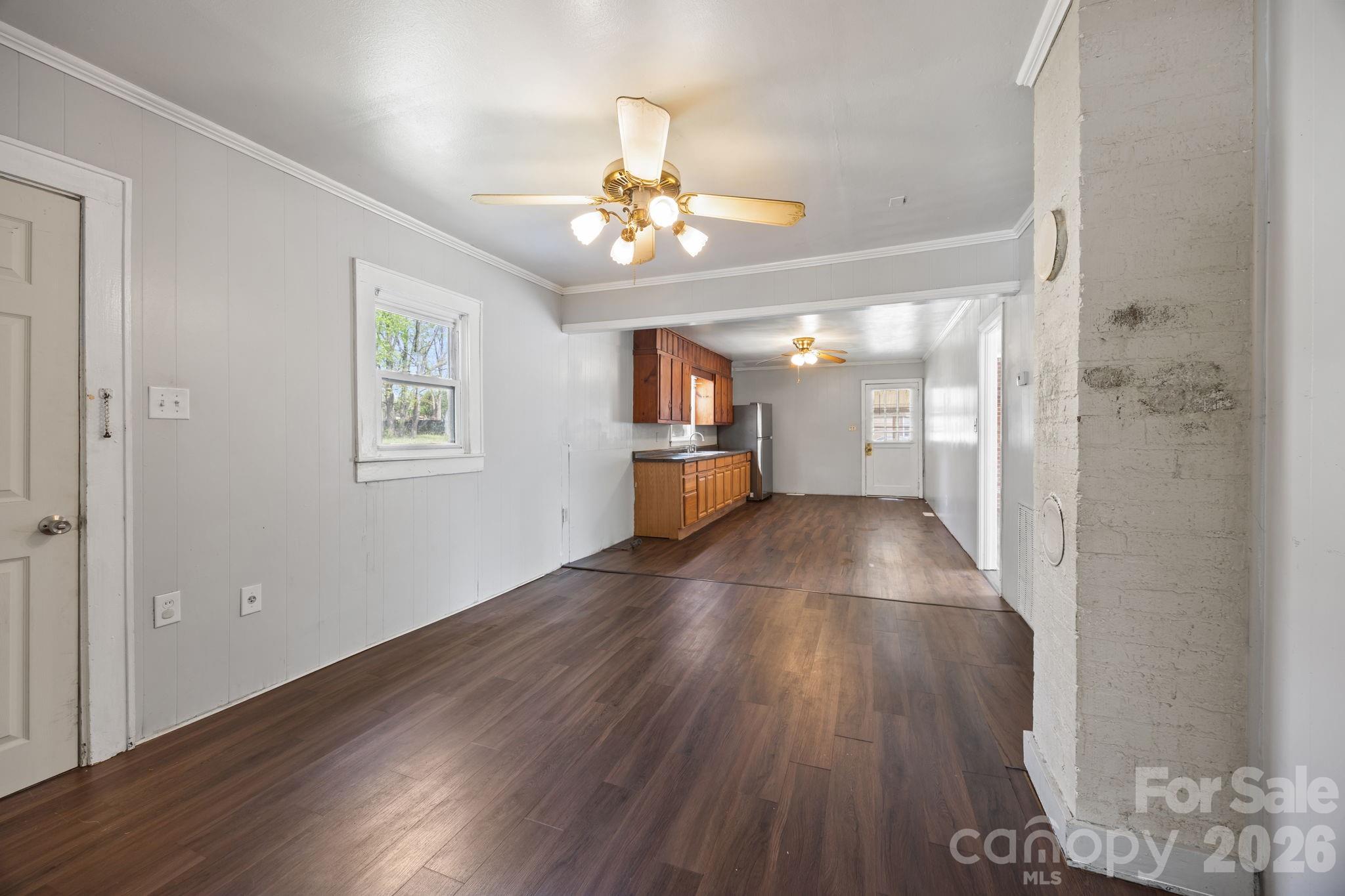208 Ellis Street Albemarle, NC 28001 - Photo 13 of 38 a view of an empty room with wooden floor and a kitchen