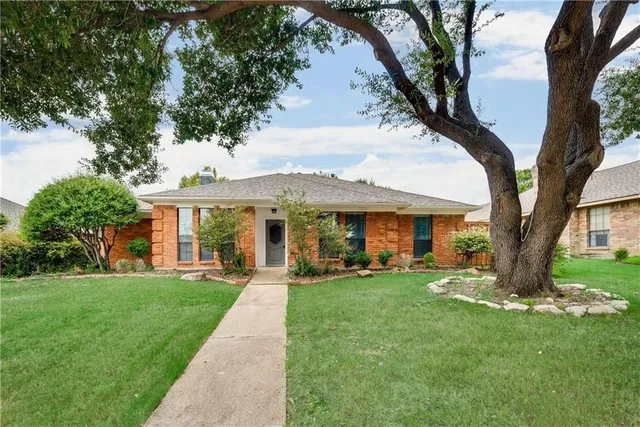 a front view of a house with a garden and trees