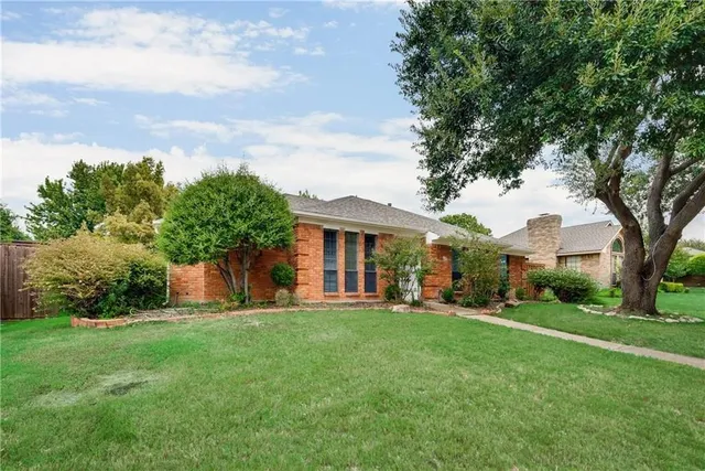 a front view of a house with a yard and trees