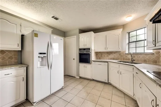 a kitchen with white cabinets and refrigerator