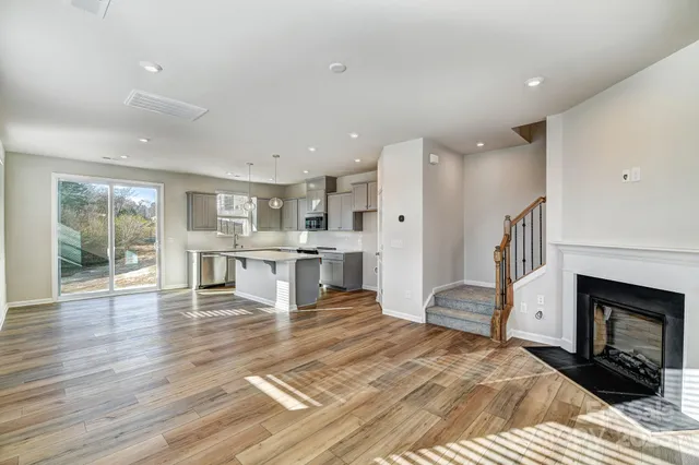 a large white kitchen with a fireplace and wooden floor