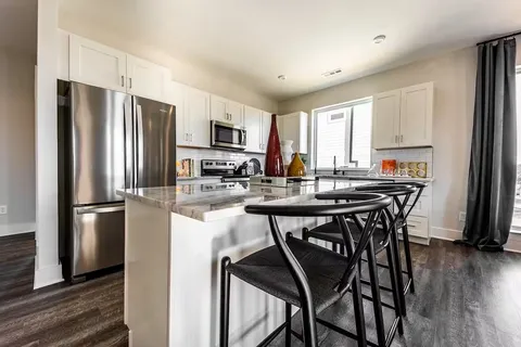a kitchen with stainless steel appliances a table chairs refrigerator and microwave