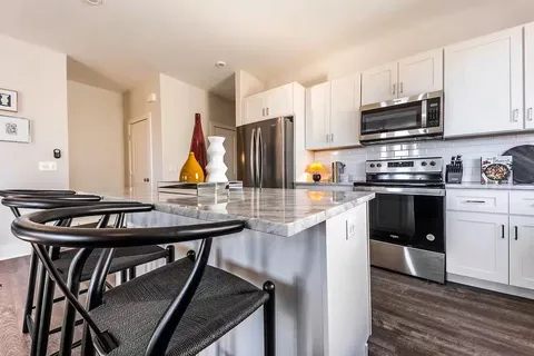 a kitchen with stainless steel appliances kitchen island granite countertop a table chairs microwave and sink