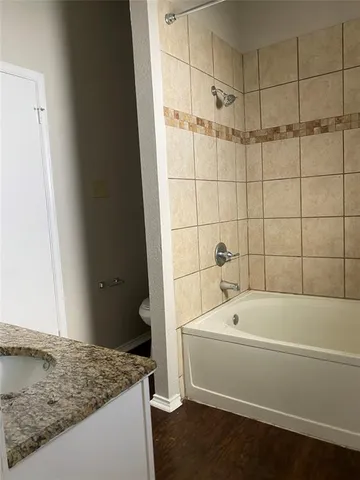 a bathroom with a granite countertop toilet a sink and bathtub