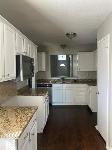 a kitchen with granite countertop white cabinets and white appliances