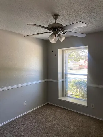 en empty room with windows and ceiling fan