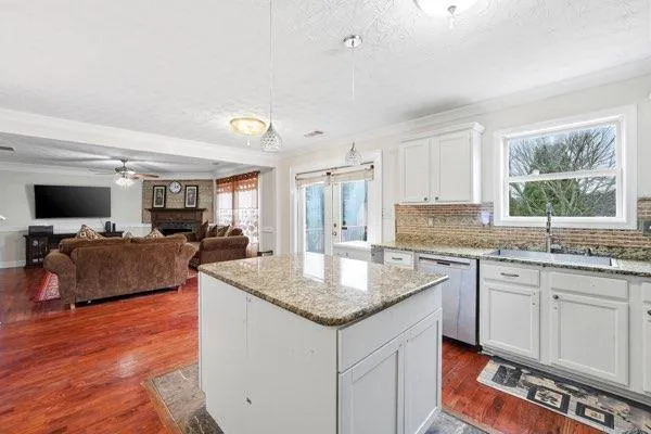 a kitchen with granite countertop a sink dishwasher a stove and a refrigerator with wooden floor