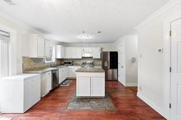 a kitchen with granite countertop a refrigerator stove top oven and sink