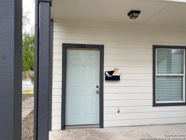 an empty room with kitchen and chandelier fan