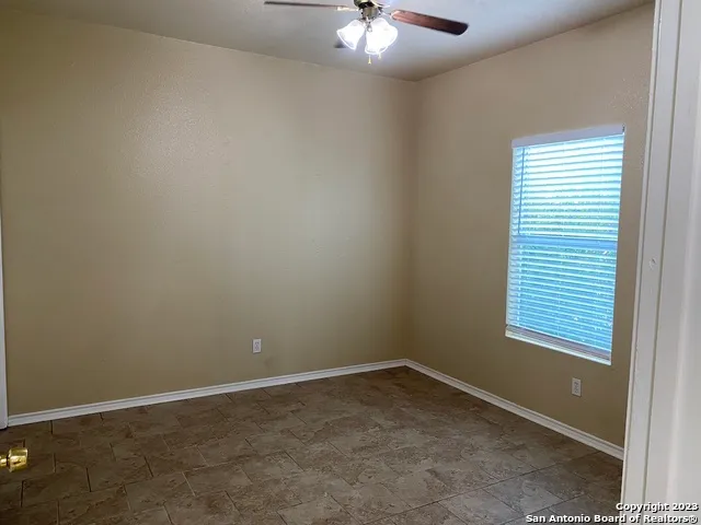 an empty room with a hallway and a chandelier fan