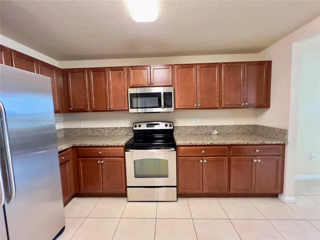 a kitchen with granite countertop a stove top oven microwave and cabinets