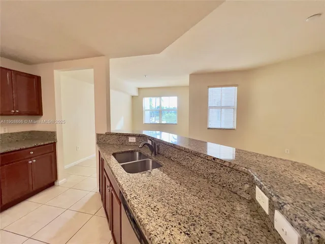 a kitchen with granite countertop a sink a stove and cabinets