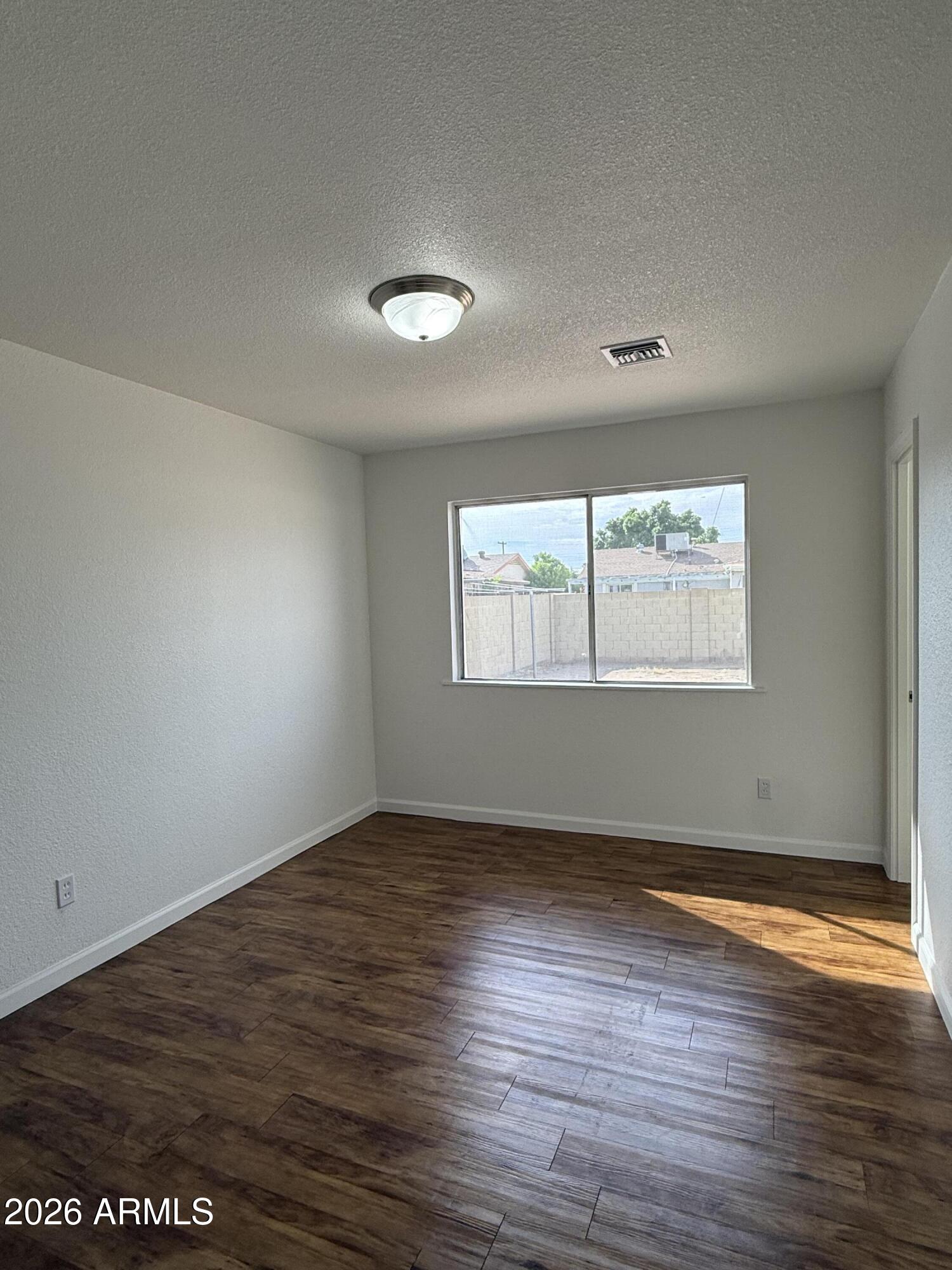 5807 West Flower Street Phoenix, AZ 85031 - Photo 9 of 11 an empty room with wooden floor and windows