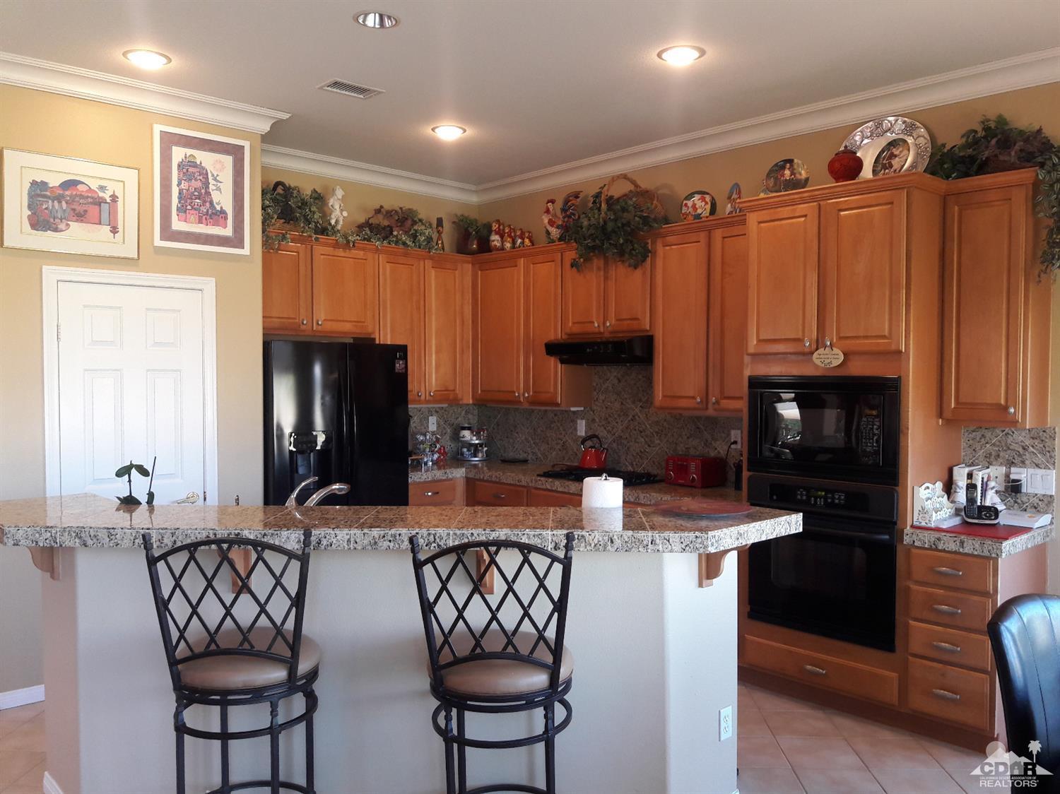 80546 Knightswood Road Indio, CA 92201 - Photo 8 of 35 a kitchen with granite countertop a refrigerator and a stove top oven