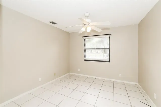 an empty room with windows and fan