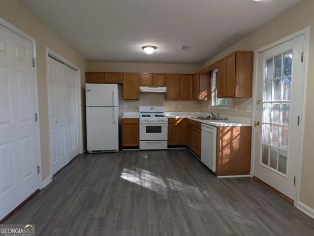 a kitchen with stainless steel appliances granite countertop wooden floors and white cabinets