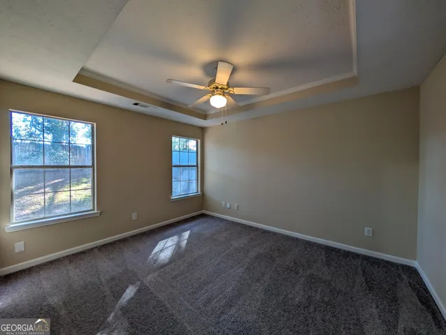 an empty room with windows and fan