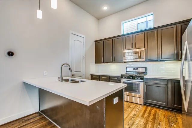 a kitchen with stainless steel appliances a sink a stove a refrigerator cabinets and a counter top space