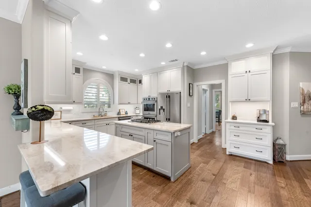 a kitchen with stainless steel appliances a sink a stove a refrigerator and cabinets