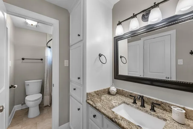 a bathroom with a granite countertop toilet sink and mirror