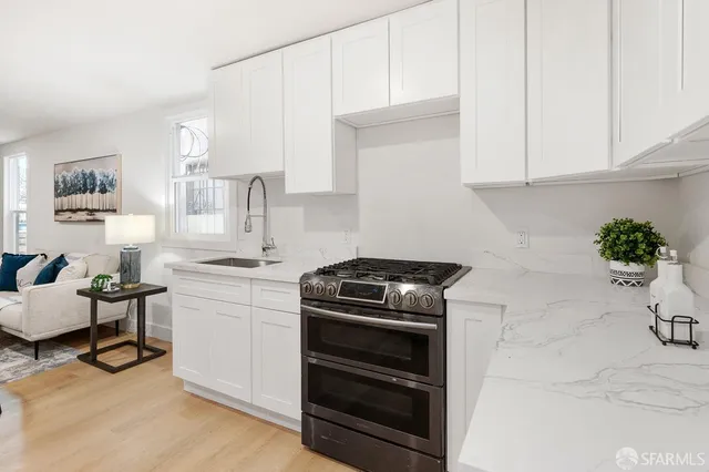 a view of a kitchen with white cabinets and wooden floor