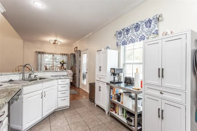 a large white kitchen with stainless steel appliances granite countertop a stove a sink dishwasher and white cabinets with wooden floor