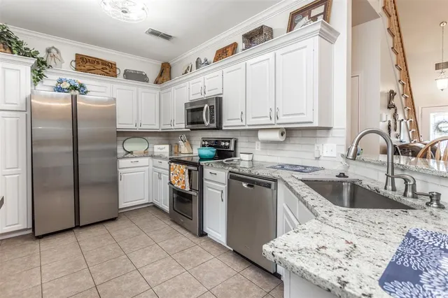 a kitchen with kitchen island granite countertop a sink a counter top space appliances and cabinets