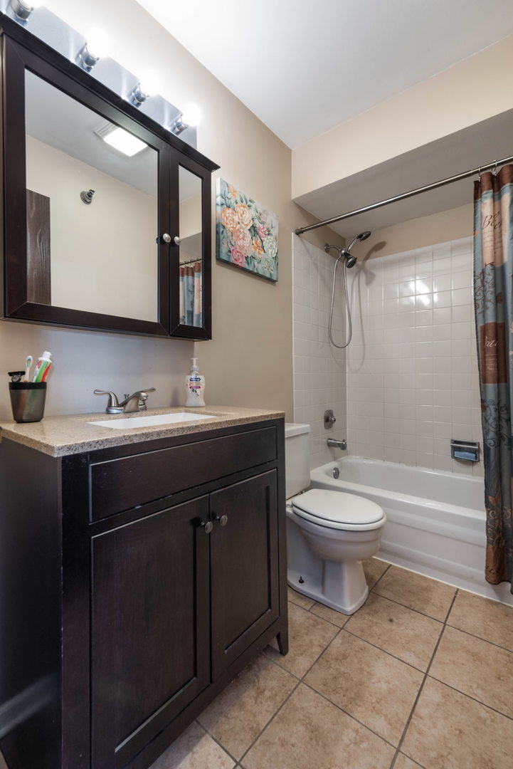 4180 Cove Lane, Unit C Glenview, IL 60025 - Photo 14 of 19 a bathroom with a toilet a sink a mirror a bathtub and vanity