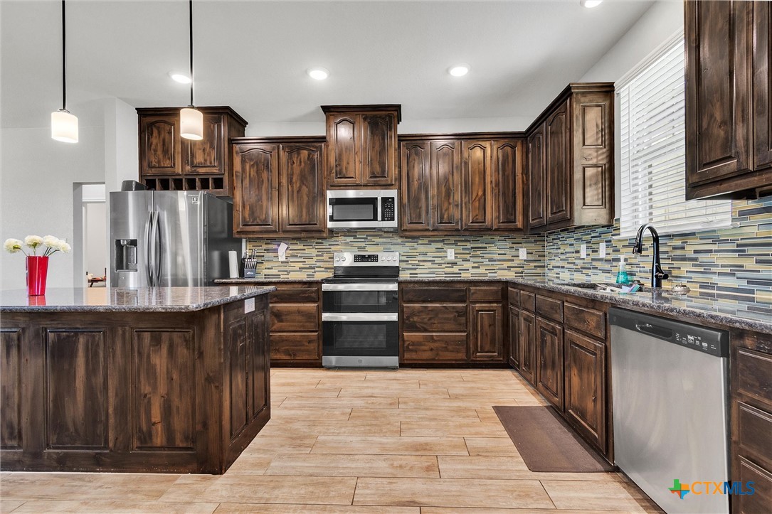 3919 Gracey Lane Kempner, TX 76539 - Photo 17 of 44 a kitchen with stainless steel appliances kitchen island granite countertop wooden cabinets a refrigerator and a sink