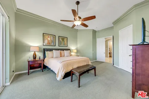 a bedroom with a bed chandelier and a window