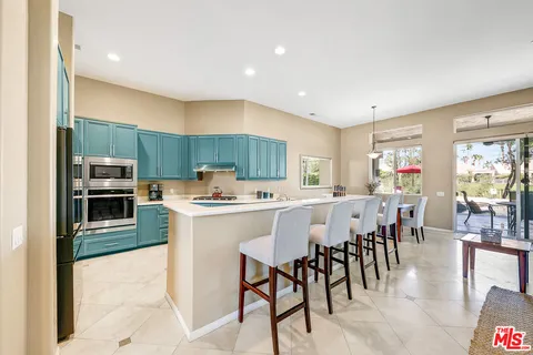 a kitchen with stainless steel appliances kitchen island granite countertop a table chairs microwave and sink